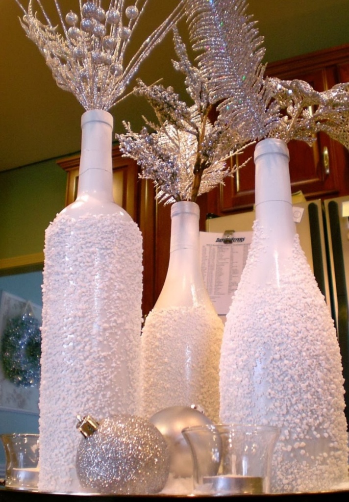 Пустые винные бутылки могут стать отличными новогодними вазами. Нужно всего лишь покрасить их в белый цвет и, пока не засохла краска, посыпать крупной солью.